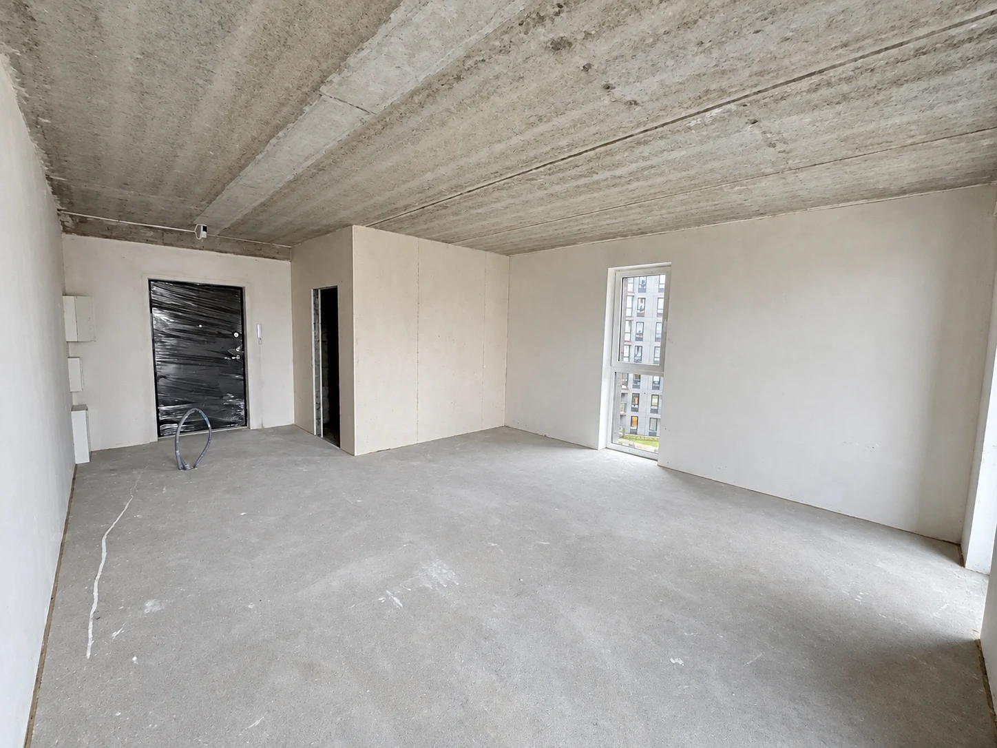 The highlighted apartment before the fit-out, with unfinished walls, exposed concrete ceiling and bare floor; lighting enhanced.